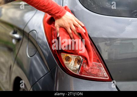 lucidare un'auto con uno straccio dopo l'autolavaggio Foto Stock