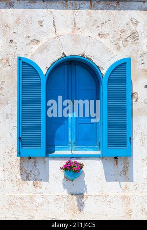 Una finestra con persiane blu a Santa Maria di Leuca, un villaggio sulla costa adriatica sulla punta meridionale della penisola salentina nell'Italia meridionale Foto Stock