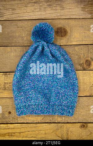 Cappello blu invernale in maglia di lana fatto a mano isolato su sfondo in legno antico Foto Stock