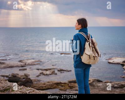 Viaggia verso l'antica città di Side, la costa di Antalya in Turchia in bassa stagione turistica. donna turista guarda al sole sul mare Foto Stock