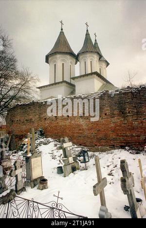 Tutana, Contea di Arges, Romania, 2000. Vista esterna di St La chiesa di Atanasio presso il monastero di Tutana, un monumento storico del XV secolo. Cimitero e rovine delle mura difensive. Foto Stock