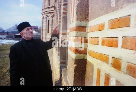 Tutana, Contea di Arges, Romania, 2000. Padre Gheorghe Baranescu fuori da St. La chiesa di Atanasio presso il monastero di Tutana, un monumento storico del XV secolo. Foto Stock