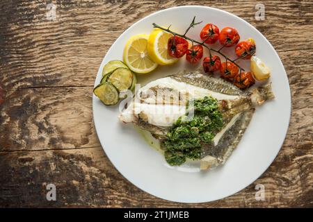 Un John Dory grigliato, Zeus faber, pescato nella Manica servito con salsa alle erbe. Dorset Inghilterra Regno Unito GB Foto Stock