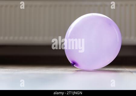 Un ritratto di una mongolfiera viola che giace su un pavimento di una casa. L'oggetto decorativo è esploso e pronto per essere utilizzato da bambini o adulti Foto Stock