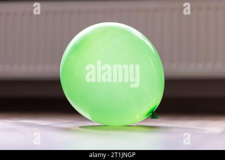 Un ritratto di una mongolfiera verde sdraiata su un pavimento di una casa. L'oggetto decorativo è esploso e pronto per essere giocato da bambini o adulti e da usare Foto Stock