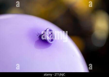 Un ritratto del nodo nel collo e nel labbro di un palloncino viola. La decorazione festiva è pronta per essere utilizzata da bambini o adulti Foto Stock