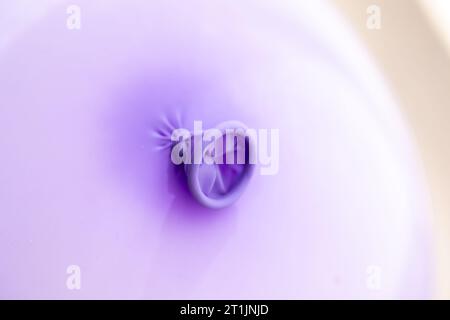 Primo piano del nodo nel collo e nel labbro di un palloncino viola. La decorazione festiva è pronta per essere utilizzata da bambini o adulti Foto Stock