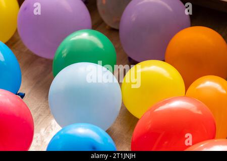 Un primo piano di più palloncini vibranti che si trovano sul piano di un soggiorno al coperto di una casa. Le decorazioni divertenti sono pronte per una festa di compleanno a casa o anni Foto Stock