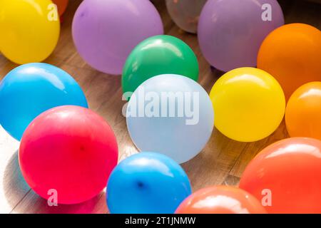 Un ritratto di più palloncini colorati che si trovano sul pavimento di un soggiorno al coperto di una casa. Le decorazioni divertenti sono pronte per una festa di compleanno a casa o per una festa Foto Stock