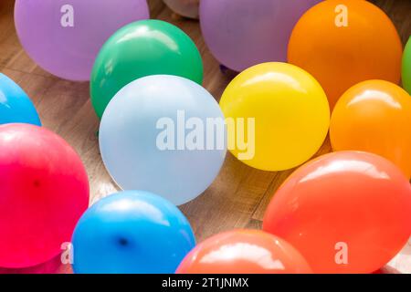 Un ritratto di più palloncini colorati che si trovano sul pavimento di un soggiorno al coperto di una casa. Le decorazioni divertenti sono pronte per una festa di compleanno a casa o per una festa Foto Stock