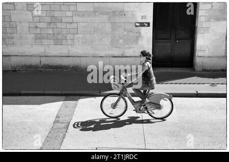 Donna che va in bicicletta per strada a St. Germain, Parigi, Francia Foto Stock