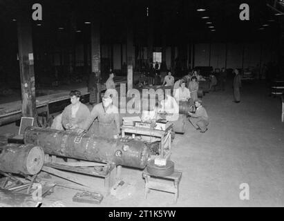 La vita al Royal Navy armamento Depot Frater, Gosport, 25-30 Luglio 1944 A RNAD Frater, la miniera depot somministrati da RNAD Priddy's Hard, Gosport lavoratori di sesso maschile e di sesso femminile il montaggio del complesso quadro della strumentazione a caricato miniere. Questo pannello contiene il meccanismo che consente di impostare la miniera off. Ciascun pannello è pesantemente imbottita con gomma del sorbo e si è detto quando una miniera era caduto accidentalmente dall'aria su di una pista in cemento del quadro della strumentazione sono sopravvissuti allo shock intatto. Foto Stock