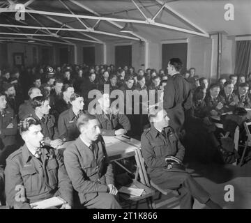 Royal Air Force Bomber Command, 1942-1945. Squadron Leader Peter Hill, mutandine equipaggi di n. 51 Squadron RAF sulla prossima raid a Norimberga, Germania nella sala operativa a Snaith, Yorkshire. Il comandante della stazione, capitano di Gruppo N H Fresson, siede il terzo da sinistra in prima fila. No. 51 Squadron perso sei Handley Page Halifaxs quella notte (30/31 marzo 1944), sofferenza 35 uomini ucciso (compresi Sqn Ldr Hill) e sette fatti prigionieri di guerra. Foto Stock