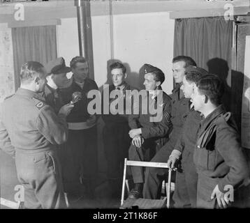 Royal Air Force Bomber Command, 1942-1945. BBC corrispondente di guerra Richard Nord interviste l'equipaggio di Avro Lancaster 'S dello zucchero" di n. 630 Squadrone RAF al loro ritorno in Oriente Kirkby, Lincolnshire, dopo aver bombardato gli scali di smistamento a Juvisy-sur-Orge, Francia. Foto Stock