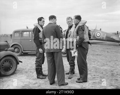 Royal Air Force Fighter Command, 1939-1945. Il funzionario dei servizi segreti di n. 19 Squadron RAF (torna alla telecamera) riceve i piloti degli account di una sortita a Fowlmere, Cambridgeshire. I piloti sono (da sinistra a destra): Squadron Leader B J E 'sandy' Lane (squadrone ufficiale in comando) Flight-Lieutenant W J "agricoltore" Lawson sergente D Lloyd Foto Stock