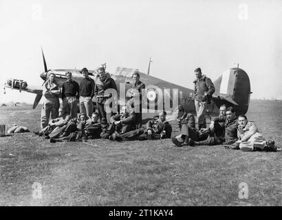 Royal Air Force operazioni in Albania e Grecia, 1940-1941. I piloti di n. 33 Squadron RAF, a Larissa, Grecia, con Hawker Hurricane contrassegnare I, V7419, in background. In piedi da sinistra a destra); gli ufficiali pilota W Winsland, R Dunscombe (p.o.w 22 maggio 41), C C Chetham (k.i.a. 15 41 Aprile), e P R W Wickham, battenti ufficiali D T Moiré e H J Starrett (morto di ustioni 22 41 aprile): seduta (da sinistra a destra); UFFICIALE DI VOLO E J 'Timber " Boschi (k.i.a. 17 Giugno 41), ufficiale di volo F Holman (k.i.a. 20 maggio 41), Volo tenente un M Giovani, ufficiale di volo V C 'woody' Woodward, Squadron Leader M St J 'Pat' Pattl Foto Stock