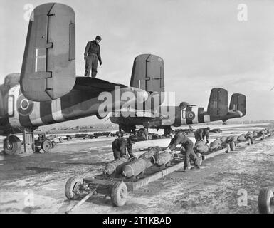 Royal Air Force - la seconda forza aerea tattica, 1943-1945. RAF e navali olandesi gli equipaggi di terra preparare per il carico da 500 lb MC bombe nel nord americano Mark Mitchell IIs di n. 98 Squadron RAF, in condizioni invernali a B58/Melsbroek, Belgio. Foto Stock