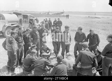 Royal Air Force - la seconda forza aerea tattica, 1943-1945. Hawker Typhoon piloti di n. 121 e 124 Ali discutere le operazioni a B2/Bazenville, Normandia, la sera del 14 giugno 1944. In primo piano, in piedi a sinistra, sono cinque i piloti di n. 175 Squadrone RAF, compreso il comandante, Squadron Leader M R Ingle-Finch (il quarto da sinistra): sul supporto destro membri di n. 181 Squadrone RAF con il loro comandante, Squadron Leader C D 'kit' North-Lewis seduti all'estrema destra. Nel gruppo più lontano, quelli identificati comprendono Wing Commander C L verde (indossando il casco) leader di n. 121 Ala, un Foto Stock