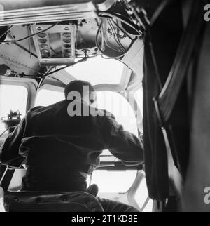 Il navigatore al lavoro in un Lockheed Hudson di n. 269 Squadrone volare un 'ice patrol' oltre la Danimarca stretto tra l'Islanda e la Groenlandia, maggio 1942. U-barche sono state non solo la minaccia per i convogli in latitudini settentrionali. Un orologio doveva essere mantenuto sul pack artico-ghiaccio, la misura e la cui composizione possono variare a seconda del momento dell'anno. A tal fine n. 269 Squadrone in Islanda ha volato regolari "pattuglie di ghiaccio sopra la Danimarca stretto tra l'Islanda e la Groenlandia. Qui, il navigatore funziona nel naso di un Hudson, maggio 1942. Come mai la sortie dipendeva estremamente accurata la navigazione. Foto Stock