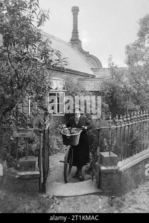 Il villaggio di invasione- La vita quotidiana in Orford, Suffolk, Inghilterra, 1941 District Nurse Baker spinge la sua bicicletta fuori dal suo cancello anteriore come lei lascia la sua casa su una chiamata. L'infermiera Baker è il responsabile della locale Posti di primo soccorso e è anche sul comitato di invasione. Foto Stock