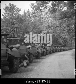 Invasione build-up- Preparativi per lo sbarco in Normandia, UK, 1944 Una linea di camion dell'esercito attende collezione lungo un viale alberato o percorso, da qualche parte in Gran Bretagna. Presto saranno raccolti dalle varie unità e trasportato al secondo fronte. In primo piano, un meccanico può essere visto lavorare su uno dei veicoli. Foto Stock
