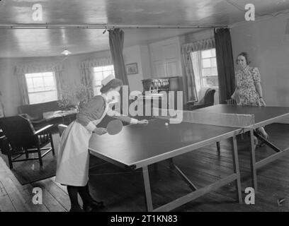 Mansion diventa maternità Home- Vita a Brocket Hall, Welwyn, Hertfordshire, 1942 due infermieri (uno in uniforme, gli altri in abiti civili) giocare a ping pong o 'ping-pong' nel loro salotto dopo una giornata intensa a Brocket Hall ospedale di maternità. Foto Stock