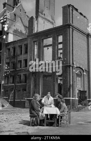 Aiuti dall America- Lend Lease cibo, Londra, Inghilterra, 1941 Un cameriere piatti su una piastra di American uova e pancetta per un gruppo di persone sedute a un tavolo al di fuori del guscio vuoto di una bomba gravemente danneggiato la scuola. La scuola ha le parole "ayer Street scuole, 1891' sulla lapide visibile sulla destra della fotografia. Questa fotografia è stata probabilmente preso a fine agosto o primi di settembre 1941. Foto Stock