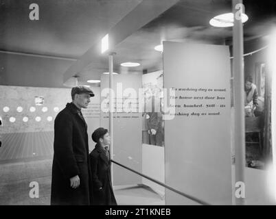 Ministero delle informazioni mostre durante la Seconda Guerra Mondiale a Londra, Inghilterra, Regno Unito, 1940 Un padre e figlio guarda i pannelli di visualizzazione al 'London Pride' esposizione, tenutasi a Charing Cross, Stazione della metropolitana. La mostra mira a mostrare ai visitatori che la vita stava andando come al solito, nonostante le incursioni aeree e altri disagi da londinesi. Foto Stock