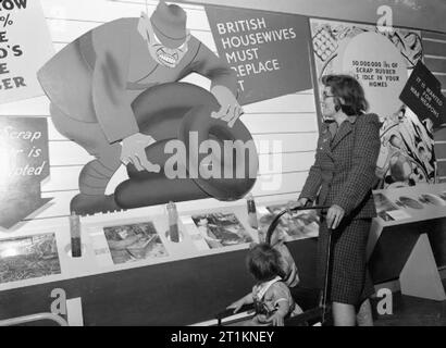 Ministero delle informazioni mostre durante la Seconda guerra mondiale, Oxford, Oxfordshire, England, Regno Unito, 1942 Una donna e i suoi due figli guardare un grande pannello di visualizzazione circa il recupero di gomma ad una esposizione di soccorso in Oxford. Foto Stock