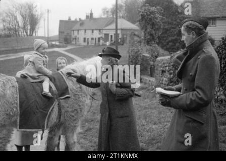 Onorevole Bugler va alla guerra - La vita quotidiana in Oriente Dean, Sussex, Inghilterra, 1943 La signora Bugler si ferma per dire ciao a un giovane ragazzo, Jimmy Gilbert, chi è a cavallo di un pony. Jimmy è il nipote del grande Harding, il villaggio scudiero. Il soldato a destra della fotografia, il Tenente Brian Scott, è contribuire a portare le parcelle per la onorevole Bugler. Foto Stock