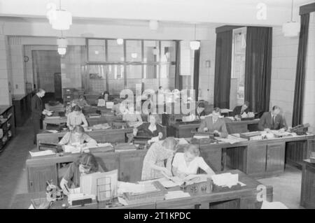 La gente al lavoro in tempo di guerra - La vita quotidiana in tempo di guerra la Gran Bretagna, 1940 Uomini e donne al lavoro come commessi e dattilografi in un ufficio generale da qualche parte in Gran Bretagna, 1940. Foto Stock