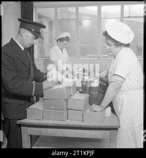 L'aeroporto di Prestwick- Trasporti e viaggi in tempo di guerra, Prestwick, Ayrshire, in Scozia, Regno Unito, 1944 Stazione BOAC Steward Eldridge prepara la cena scatole in cucine presso l'aeroporto di Prestwick, come uno del personale della cucina fa palloni. Queste scatole sono per il 16 passeggeri ed equipaggio 5 viaggia quella sera. La didascalia originale afferma che in tempo di pace, signor Eldridge serviti pasti caldi in volo. Foto Stock