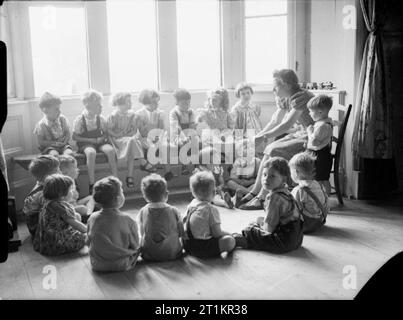 Gli aiuti americani per la Gran Bretagna- Vita a corte Syston nursery, Sara Delano Roosevelt Home, Gloucestershire, Inghilterra, 1942 bambini seduti in cerchio, alcuni sul pavimento e altri sulla finestra sedile, per ascoltare una storia raccontata alla Corte Syston vivaio nel Gloucestershire. Foto Stock