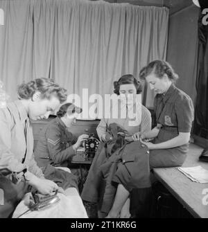 Servizi Club- il lavoro delle donne del volontariato a Chester House, Clarendon Place, Londra, Inghilterra, 1943 Donne della ATS fanno uso di laboratorio presso i servizi Club a Chester House. Una macchina da cucire, ferro da stiro e rammendo materiali sono forniti da WVS per i membri del club. Qui, Miss Albrecht (a destra), il supervisore di catering del ramo di Paddington del WVS, aiuta a un membro della ATS per cucire un pulsante sulla sua tunica. Foto Stock