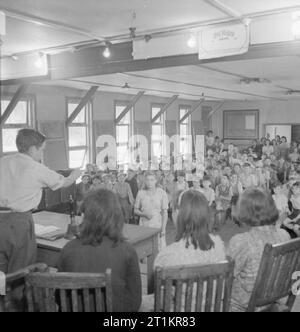 Scuola per sfollati- Vita quotidiana a Marchant collina del Camp, Scuola Hindhead, Surrey, England, Regno Unito, 1944 Una scuola riunione in corso a Marchant's Hill School, Hindhead. Presiede la riunione è di 14 anno Old Vic Randall (sinistra). L incontro si è svolto in una delle grandi capanne di legno che servono come alloggio e aule della scuola. Foto Stock