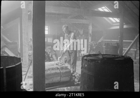 Sticky Bomb- la produzione del n. 74 Granata in Gran Bretagna, 1943 operaio di fabbrica John R Jones utilizza un martello per rompere un grande blocco di resina, uno dei costituenti principali utilizzati nella produzione di miscela adesiva utilizzata su 'STICKY le bombe". Foto Stock