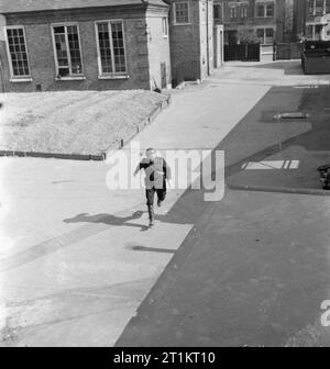 La ricostruzione di un "incidente'- Difesa Civile Formazione in Fulham, Londra, 1942 un raid aereo precauzioni operaio corre al suo posto con una relazione dell'incidente verificatosi nella zona. ARP questo post è chiaramente basato in un edificio scolastico ed è possibile che si tratti di Mary Boon Scuola sull'angolo del Vescovo re della strada e Earsby Street, vicino a Avonmore Road, Fulham. Foto Stock