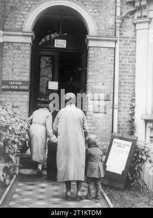 Il lavoro dei cittadini Advice Bureau, Eldon House, Croydon, Inghilterra, 1940 due donne e i loro bambini arrivano in corrispondenza dei cittadini Ufficio di consulenza per chiedere maggiore indennità. Foto Stock