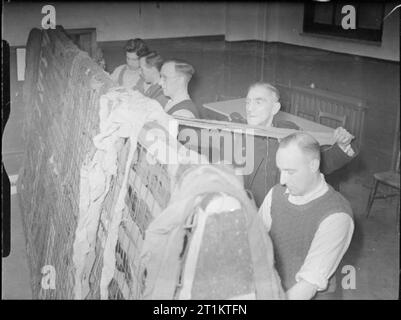 Essi hanno anche lotta che solo il supporto e attendere- gli uomini del Servizio Nazionale dei Vigili del Fuoco non guerra Extra Lavoro, London, 1942 uomini del Servizio Nazionale dei Vigili del fuoco rendono il camuffamento reti a Battersea la stazione dei vigili del fuoco. Foto Stock