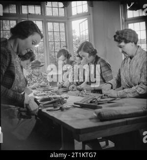 Essi hanno anche lotta che solo il supporto e attendere- part-time lavoro guerra a Croydon, Surrey, Inghilterra, 1943 Part-time donne lavoratori guerra sedersi attorno a un tavolo di grandi dimensioni e assemblare le gambe di compressione di quello che una volta era la sala da pranzo in questa casa, ora utilizzata come un ripiego in officina o in fabbrica. Foto Stock