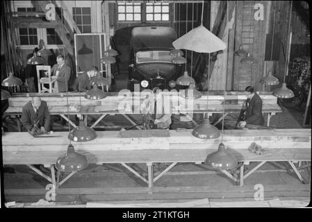 Essi hanno anche lotta che solo il supporto e attendere- industria bellica in una vecchia casa di campagna, 1942 uomini al lavoro in garage attaccato al signor e la signora Clark country house, ora utilizzato come una piccola fabbrica di produzione di apparecchiature di comunicazione. Una vettura può essere visto in background. Foto Stock