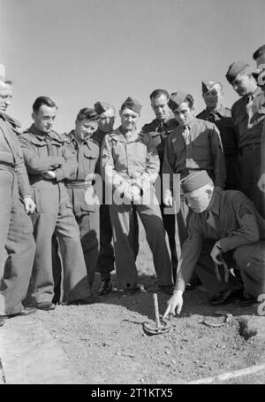 Le truppe USA in un Villaggio Inglese- La vita di tutti i giorni con gli americani in Burton Bradstock, Dorset, England, Regno Unito, 1944 sotto il sole presso la American camp a Burton Bradstock, sergente James F Hokanson (di 1062 McLemore, Memphis, Tennessee) spiega come fare il gioco dei ferri di cavallo "' a soldati di un British unità proiettore che vi soggiornarono nelle vicinanze. La didascalia originale afferma che "i due eserciti presto fatto amici, visitare altri campi, mangiare insieme, giocare". Foto Stock