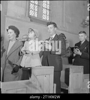 Villaggio Chiesa- La vita quotidiana in Uffington, Berkshire, Inghilterra, Regno Unito, 1944 membri della congregazione si uniscono per cantare un inno durante Evensong presso la chiesa di Santa Maria Vergine, Uffington, Berkshire. Foto Stock