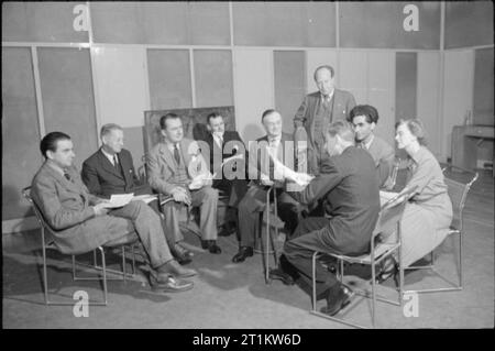 Rispondendo si- produzione di un Bbc Radio Programma per gli Stati Uniti d'America, 1941 una scena in studio durante la trasmissione di "rispondere a voi". Da sinistra a destra del pannello sono: Tom Harrisson, opinione pubblica esperto e co-fondatore di Mass-Observation; Sir Henry Bunbury; Edward Hulton, casa editrice titolare; District Officer A F Locke, un vigile del fuoco; L S Amery, Segretario di Stato per l'India; W J Brown, Segretario del Servizio Civile Associazione clericale; e Z A Bokhari, poeta ed emittente e un indiano che vivono a Londra. Sono presenti anche la onorevole Vyvyan Adams e, con il suo ritorno al fornito Foto Stock