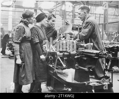 Le donne di fabbrica il lavoro di guerra a Slough Training Center, England, Regno Unito, 1941 tre donne lavoratori ricevono istruzioni sul progetto di un cabestano macchina da un collega di sesso maschile in officina a Slough Training Center. Foto Stock