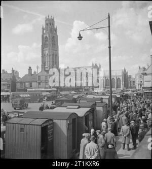 Mercato Boston- il paese mercato e Fiera di Maggio, Boston, Lincolnshire, Inghilterra, Regno Unito, 1945 agricoltori raccolgono intorno le capanne di legno di mais e i commercianti di bestiame, che sono state erette nel mercato posto a Boston, Lincolnshire. Chiaramente visibile tra questi è quello di "una chiesa e figli di Horncastle, vendita 'International per macchine agricole e trattori'. Sullo sfondo la torre di Boston il moncone (St Botolph's Church) può essere chiaramente visto, come possono i numerosi negozi, compreso "il beneficio negozio di calzature' e 'Broughton's". Foto Stock