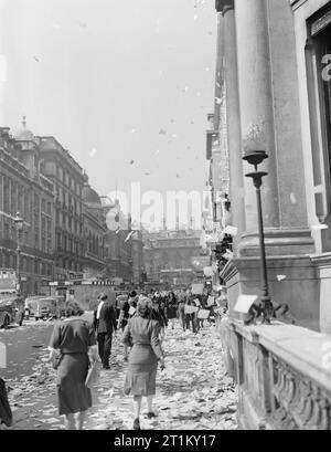 La Gran Bretagna ascolta la notizia della fine della guerra Jap- celebrando la vittoria in Giappone, Londra, Inghilterra, Regno Unito, c 15 agosto 1945 i civili a piedi tra le pile dei residui di carta che sono stati gettati, 'ticker tape'-stile, dalle finestre degli uffici, sul Lower Regent Street, Londra, per celebrare la firma della pace con il Giappone. Più carta può essere visto che fluttua in giù sul marciapiede e strada: molti veicoli sembrano essersi fermato. Sembra che questa fotografia è stata presa sul Lower Regent Street, guardando indietro verso Piccadilly Circus. In mezzo alla strada (a sinistra della fotografia), una superficie in mattoni shelte Foto Stock