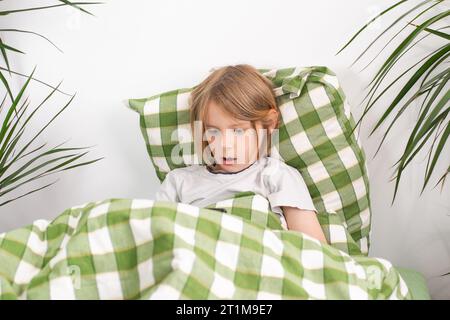 Il letto marcisce. Con il suo tablet in mano, il giovane si siede comodamente sul letto, esplorando Internet al suo ritmo Foto Stock