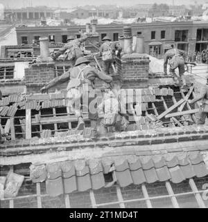 L'Esercito Britannico nel Regno Unito 1939-45 soldati clambering attraverso shattered tetti durante combattimenti di strada di formazione in un bombardato-fuori area nell'East End di Londra, 26 giugno 1942. Foto Stock