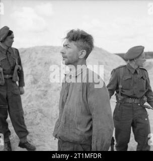 La liberazione di Bergen-belsen Campo di Concentramento, Aprile 1945 Dr Klein, un medico SS, che ha impegnato per la morte di migliaia di uomini, donne e bambini. In alcuni casi la sperimentazione su le sue vittime iniettando loro con benzina in modo da indurire il loro arterie. Mostra immagine: Dr Klein parlando di Movietone News sound carrello davanti al sepolcro in cui sono sepolti alcune delle sue vittime. Foto Stock